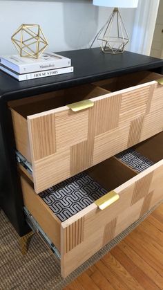 two drawers are open on the side of a black table with books and a lamp