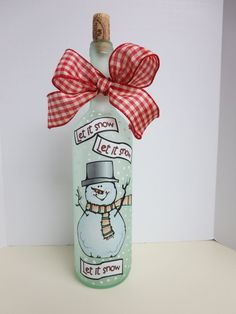 a glass bottle with a snowman on it and a red bow around the neck