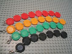 many different colored buttons are attached to a chain on a lego surface that is laid out