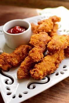 fried chicken sticks with ketchup and dipping sauce on a white serving tray, ready to be eaten