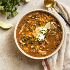 a bowl of chicken tortilla soup with sour cream and cilantro on the side