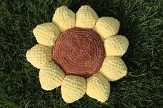 a crocheted sunflower laying on top of green grass in the middle of it's petals