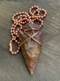 "This arrowhead pendant is a hand knapped modern replica that I artistically wrapped in pure, organic copper wire. The pendant comes with a 22\" solid copper ball chain. This style necklace is perfect for both men or women. The arrowhead is a symbol of strength, warrior spirit and the archer. Copper is the traditional gift for the 7th Anniversary. Copper is the traditional gift for the 7th wedding anniversary. READY TO SHIP! All jewelry from my studio arrives attractively packaged and ready for Brown Arrowhead Necklace For Gift, Rustic Arrowhead Necklace For Gift, Wire Wrapped Arrowhead, Arrowhead Jewelry, Wrapping Crystals, Arrowheads Jewelry, Arrowheads Design, Arrowhead Pendant, Wire Pendants