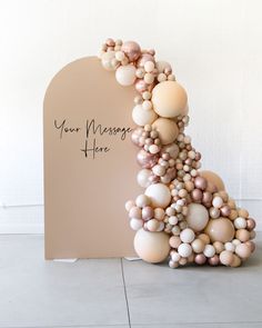 a sculpture made out of balloons on top of a white floor next to a sign that says your message here