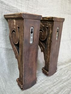 two wooden brackets are holding cell phones on the back of each other, one is turned upside down