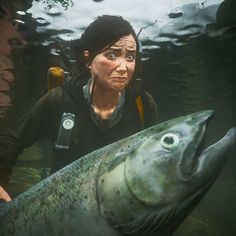 a woman holding a large fish in her hand and looking at it's camera