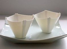 four white vases sitting on top of a plate