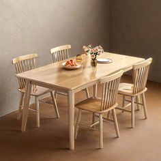 a wooden table with four chairs around it and plates of food on the dining room table