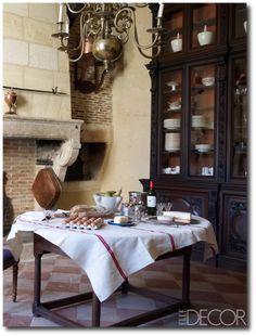 a table with bread and wine on it in front of a brick wall, chandelier