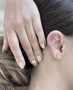 a woman with her hand on the back of her head and ear piercings behind her ear