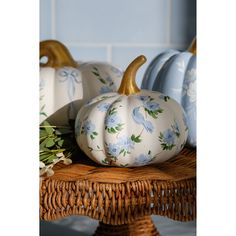 some white and blue painted pumpkins sitting on a wicker table