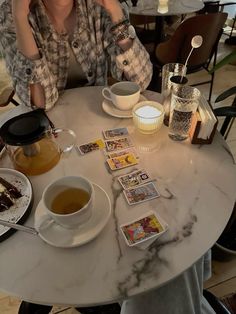 a woman sitting at a table with tea and cards on the table next to her