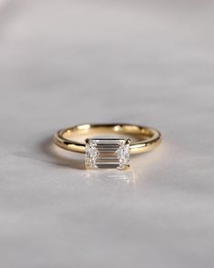 a gold ring with an emerald cut diamond