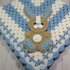 a blue and white crocheted blanket with a teddy bear on it