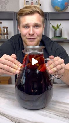 a man sitting at a table with a pitcher filled with liquid and holding it in his hands