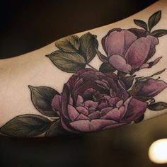 a close up of a person's arm with a flower tattoo on the arm