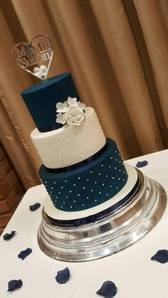 a three tiered blue and white wedding cake on top of a table with confetti