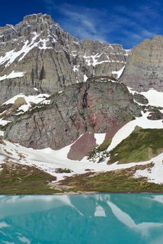 the mountains are covered with snow and blue water in front of them is a lake