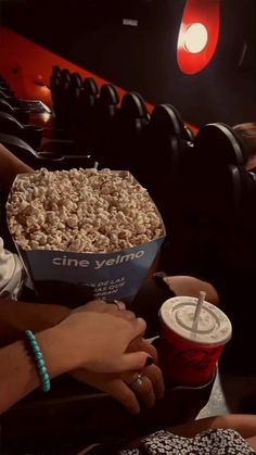 people are eating popcorn and drinking sodas at the movie theater while one person is holding a drink