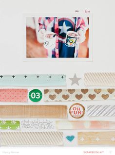 an assortment of scrapbooking papers and stickers on a white wall with a photo hanging above them