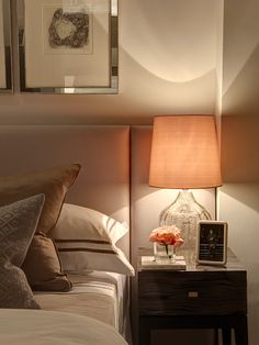 a nightstand with a lamp and some pictures on the wall