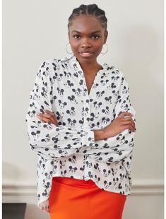 a woman in an orange skirt and mickey mouse shirt is standing with her arms crossed