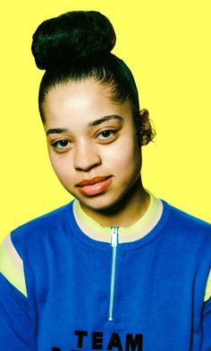 a woman with a bun in her hair wearing a blue shirt and looking at the camera