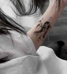 a woman with a dragon tattoo on her left arm and right arm behind her head