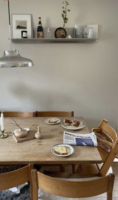 a wooden table topped with plates of food next to a wall mounted shelf filled with books