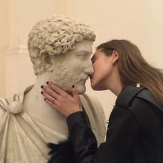 two women kissing each other in front of a statue