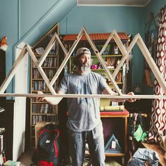 a man standing in front of a house made out of bookshelves and shelves