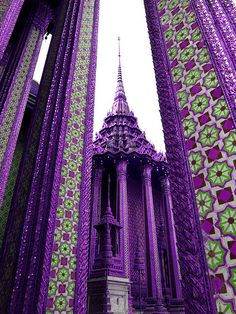 purple and green art work on the side of a building with a steeple in the middle