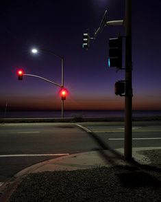 two stop lights are lit up at night by the ocean