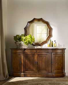 a wooden dresser sitting next to a window with a mirror on it's side