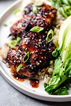 a white plate topped with chicken and broccoli covered in sesame seed flakes