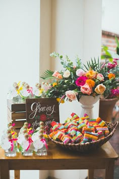 a table topped with lots of candy next to a vase filled with flowers and candies