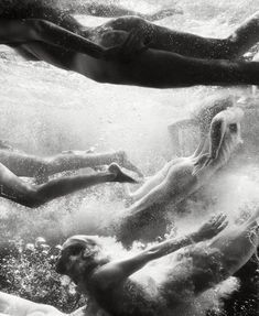 three people swimming in the water with their backs turned to the camera and arms outstretched