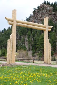 a large wooden structure sitting in the middle of a lush green field with yellow flowers