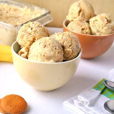 two bowls filled with ice cream next to an orange and banana on a counter top