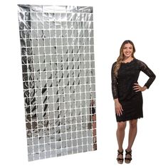 a woman standing in front of a white and black mosaic tile wall with her hands on her hips