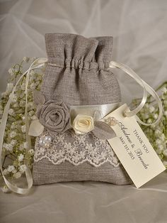 a small bag with a flower on the side and a tag attached to it, sitting next to some baby's breath flowers