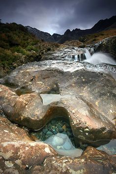 there is a small waterfall in the middle of this rocky stream that runs through some mountains