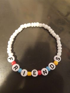 a beaded bracelet with the word friend written in white beads on a black surface