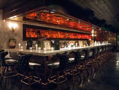 a bar with lots of stools and bottles on the back wall, all lined up