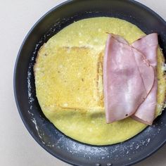 an omelet with ham on top in a frying pan, ready to be cooked