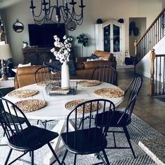 a living room filled with furniture and a chandelier above a white table surrounded by black chairs