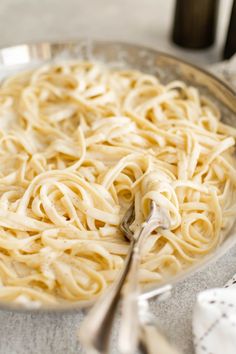 a plate full of pasta with a fork in it and two bottles on the side