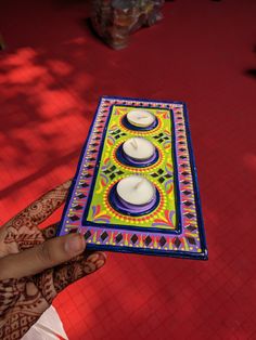 a hand holding a decorated tray with candles on it