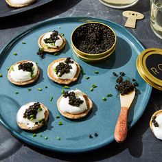 small crackers with black cavia on them sit on a blue plate