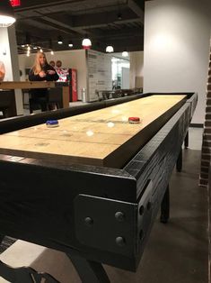 a shuffle table in the middle of a room with people playing games on the wall